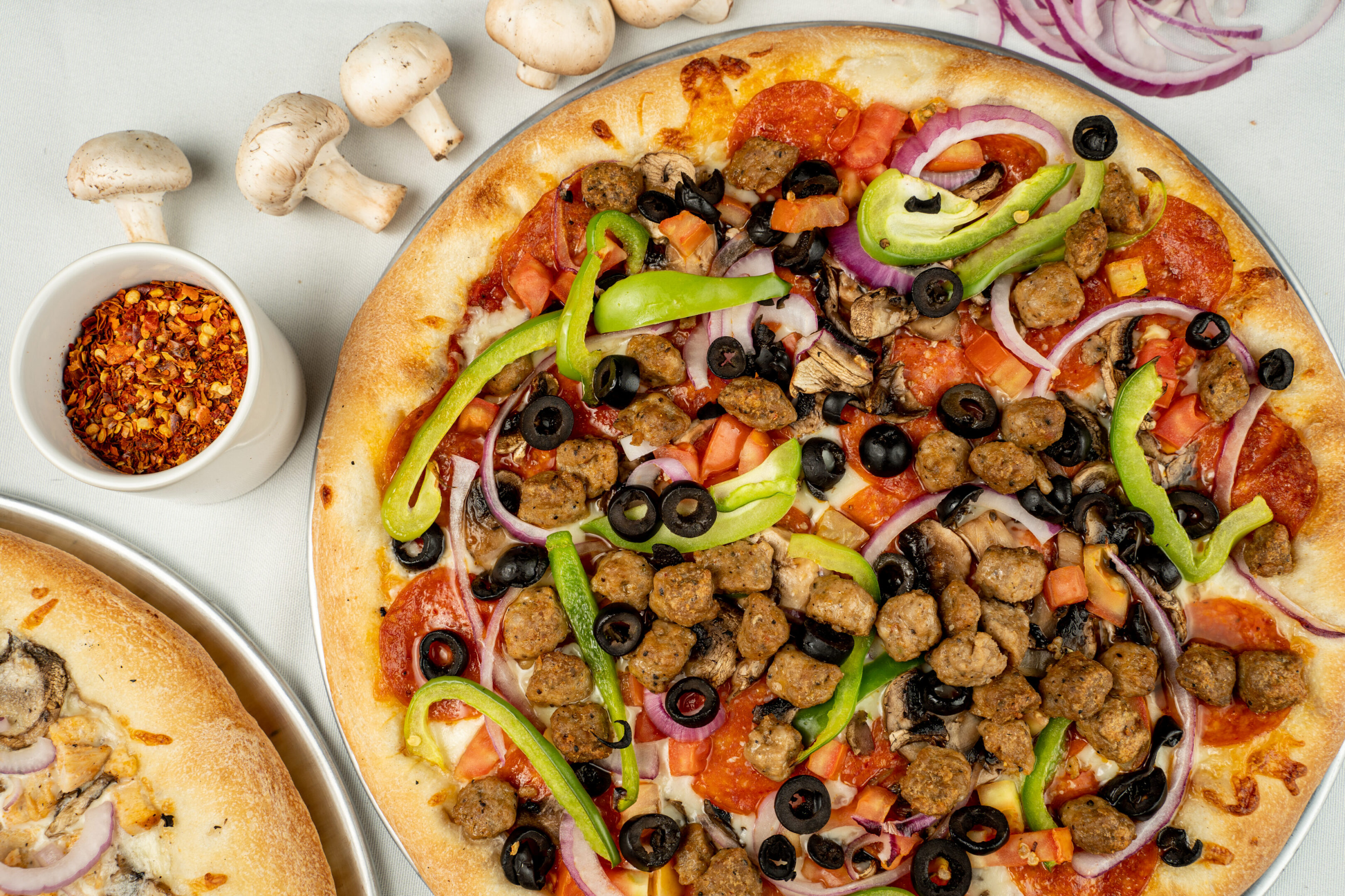 A pizza with mushrooms, peppers and olives on it.