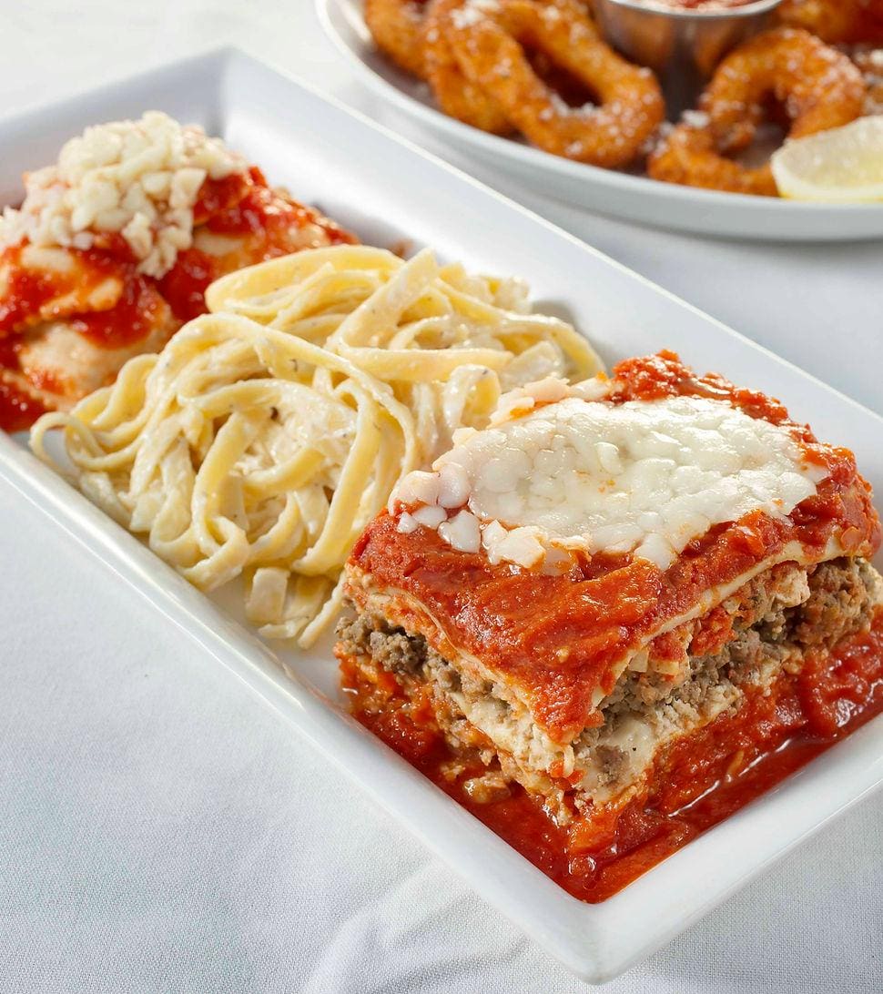 A plate of lasagna and pasta on the table.