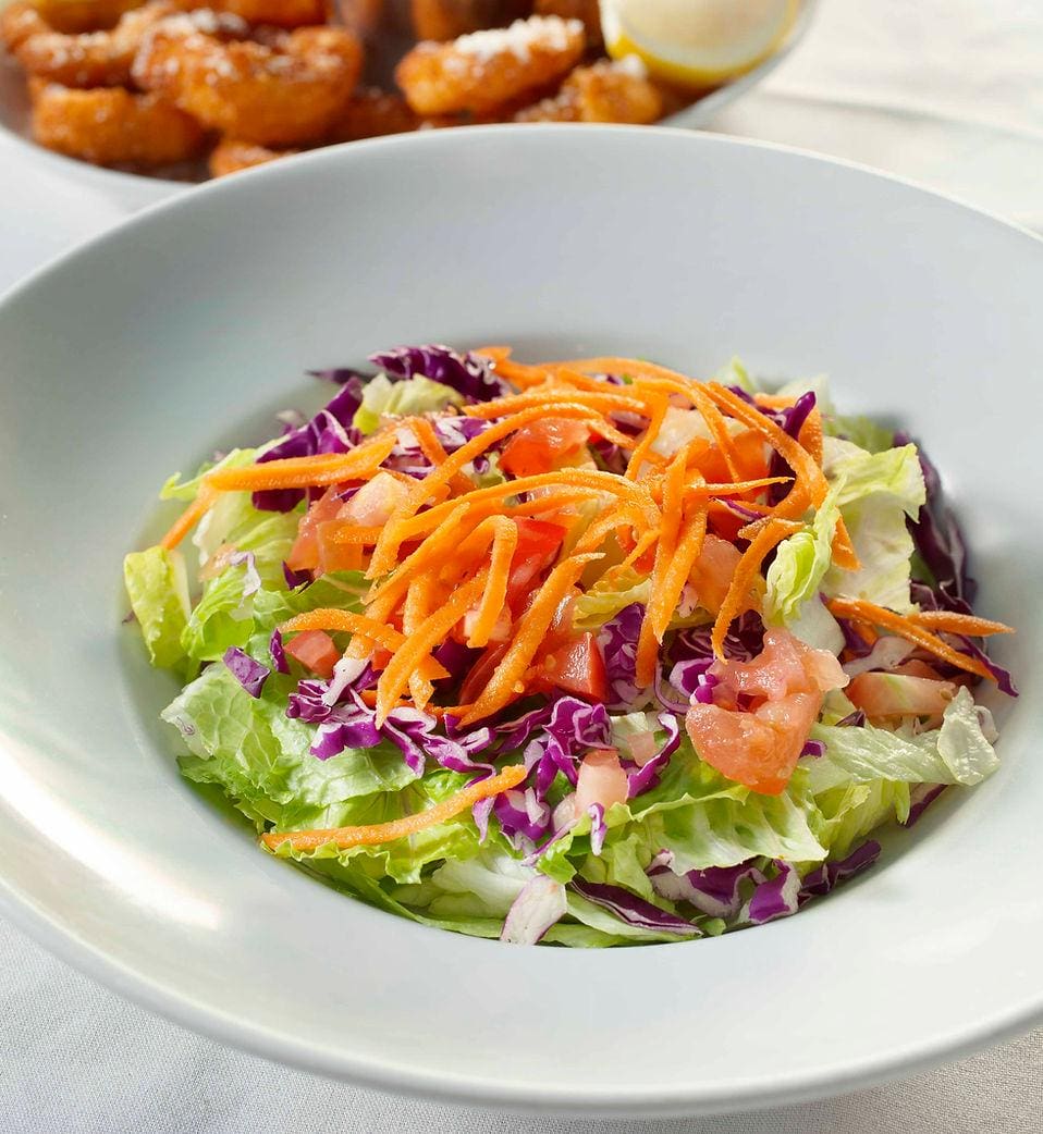 A bowl of salad with dressing on top.